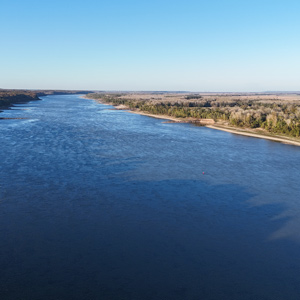 Blue sky and water below low cliffs